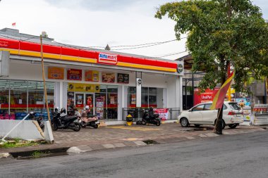 Bali, Endonezya - 25 Aralık 2024: Önünde beyaz bir araba park edilmiş Alfamart süpermarketi.