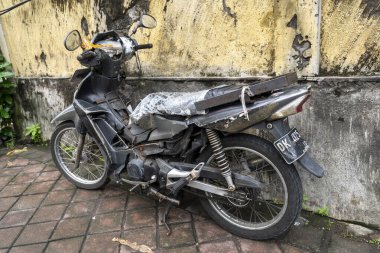 Bali, Endonezya - 25 Aralık 2024: Motosiklet yol kenarına park edilmiş. Motosiklet siyah ve plakasında DK yazıyor.