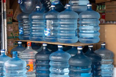 Bali, Endonezya - 25 Aralık 2024: Rafta mavi su şişeleri yığını. Şişelerin hepsi aynı boyut ve renkte.
