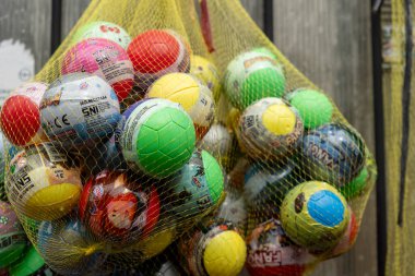 Sarı ağlı renkli toplarla dolu bir çanta. Toplar farklı renk ve boyutlarda ve bazılarında çizgi film karakterleri var. Eğlence ve oyun anlayışı