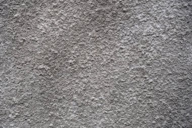 Betondan yapılmış gri duvar, pürüzlü bir dokuya sahip..