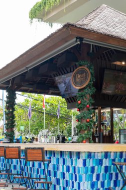 Bali, Endonezya - 25 Aralık 2024: Mavi ve beyaz fayans duvarı ve çatısı olan bar. Barda birkaç kişi oturuyor ve birkaç kişi ayakta.