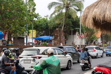 Bali, Endonezya - 25 Aralık 2024 Motosikletli yeşil tişörtlü bir adamla yoğun cadde. Yolda bir sürü araba ve motosiklet var.