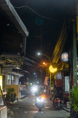 Bali, Endonezya - 25 Aralık 2024: Kuta, Bali 'de üzerinde Parlak Dövme yazan karanlık sokak. Sokak boş ve sessiz, sadece birkaç motosiklet park etmiş..