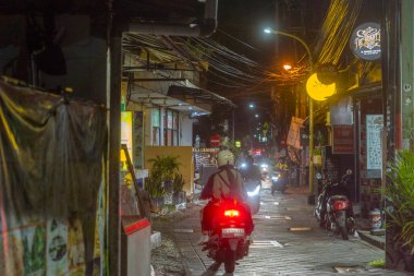 Bali, Endonezya - 25 Aralık 2024: Kuta, Bali 'de üzerinde Parlak Dövme yazan karanlık sokak. Sokak boş ve sessiz, sadece birkaç motosiklet park etmiş..