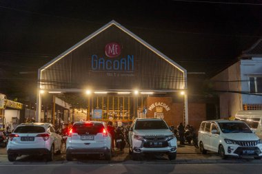 Bali, Endonezya - 25 Aralık 2024: Bir restoranın önünde üzerinde Mie Gacoan yazan bir grup araba park edilmiş. Arabalar arka arkaya park edilmiş, bazıları beyaz, bazıları siyah.