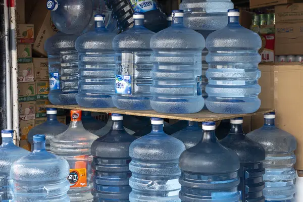 Bali, Endonezya - 25 Aralık 2024: Rafta mavi su şişeleri yığını. Şişelerin hepsi aynı boyut ve renkte.