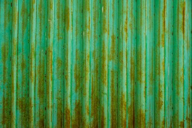 Pas dolu yeşil ve kahverengi metal bir yüzey. Pas, yüzeye eskimiş ve yıpranmış bir görünüm veriyor. Bu da nostalji ya da tarih duygusunu çağrıştırıyor.