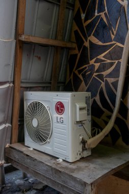 Gili, Lombok, Endonezya - 7 Ocak 2025: Beyaz LG klima ahşap bir masada duruyor. Klima kapalı ve şu an kullanımda değil. Masa duvarlı bir odada.