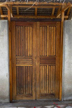 Kapı ahşaptan yapılmış ve eğimli bir çatısı var. Açık ve ahşap bir çerçevesi var.