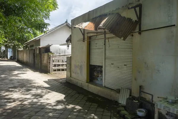 Beyaz kapısı ve metal çatısı olan küçük bir bina. Kapı açık ve yan tarafta bir pencere var.