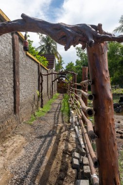 Sazdan çatılı ahşap kulübe yemyeşil bir tarlada duruyor. Kulübe ahşap bir çitle çevrilidir ve bir palmiye ağacının yanında yer alır. Huzur ve sükunet kavramı