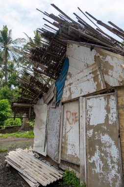 Bambu ve palmiye yapraklarından yapılmış çatılı küçük bir kulübe. Kulübe bir ormanda ve etrafında bir sürü palmiye ağacı var.