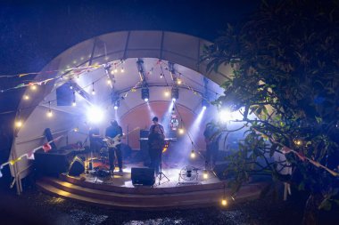 Bali, Endonezya - 26 Aralık 2024: Tipsy Lion 'da bir grup müzisyen sahne alıyor. Sahne ışıklarla aydınlanıyor ve seyirciler arasında birkaç kişi var.