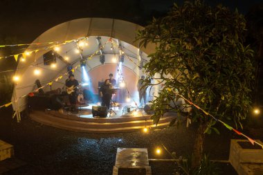 Bali, Endonezya - 26 Aralık 2024: Tipsy Lion 'da bir grup müzisyen sahne alıyor. Sahne ışıklarla aydınlanıyor ve seyirciler arasında birkaç kişi var.