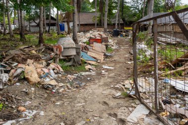 Gili, Lombok, Endonezya - 9 Ocak 2025: Çimento karıştırıcısı bir çöp yığınının içinde oturuyor. Sahne kirli ve dağınık.