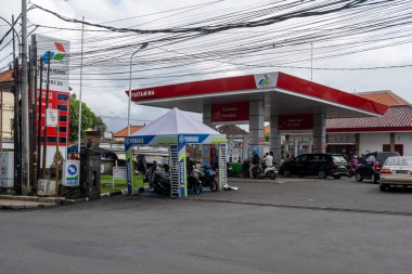 Bali, Endonezya - 29 Aralık 2024: Pertamina benzin istasyonu. Önünde Yamaha çadırı ve motosikletleri olan bir benzin istasyonu. Otoparkta birkaç araba ve motosiklet var.
