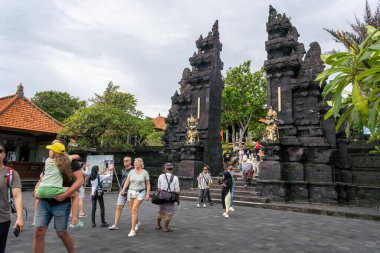 Bali, Endonezya - 29 Aralık 2024: Bir grup insan Tanah Lot kapısında bir sürü insanla yürüyorlar. Manzara canlı ve hareketli.