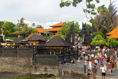 Bali, Endonezya - 29 Aralık 2024: Birçok turist Tanah Lot turistik beldesini ziyaret ediyor. Sahilde, bir kaya oluşumunun yakınında toplandılar..