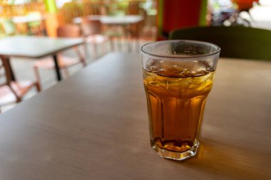 Bir bardak çay masanın üzerinde duruyor. Bardak dolu ve çay kahverengi.