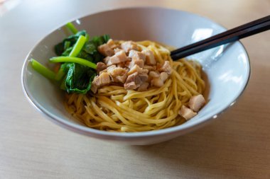 Bir kase etli ve sebzeli erişte masada duruyor..