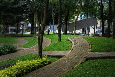 Jakarta, Endonezya - 30 Ocak 2025: Parktaki patika yeşil bitkiler ve ağaçlarla çevrilidir. Yol kıvrımlı ve taştan bir sınırı var.