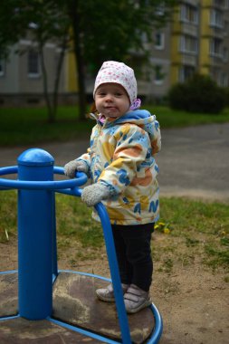 Soğuk havalarda eski Sovyet apartmanlarının yanında dönen ekipmanların üzerinde duran komik taklitçi küçük bir kız. Küçük kız sosyalist dönemin ortak alanlarında dönerek eğleniyor..
