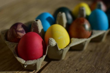 Kırık ahşap arka planda kağıt bir kutunun içindeki renkli paskalya yumurtaları. Geleneksel Avrupa paskalya yumurtaları güneşli bir günde manzarayı kapatır.