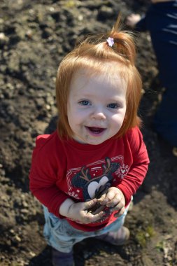 Sümüklü burunlu ve kirli yüzlü küçük kız baharda bir bahçede gülümsüyor..