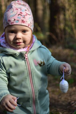 Küçük kızlar, ellerinde paskalya yumurtası süslemeleriyle ormanın içinde portre çiziyorlar. Küçük kız parkta paskalya yumurtası süslemeleriyle oynuyor. Çocukların Paskalya tatiline hazırlanması kavramı.