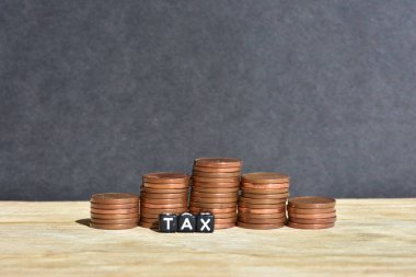 Tahta arka planda beş sütuna para yığılmış ve plastik boncuklardan yapılmış sözcük vergisi. Para ekonomisi, vergi fikri, kopyalama alanı