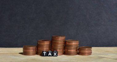 Tahta arka planda beş sütuna para yığılmış ve plastik boncuklardan yapılmış sözcük vergisi. Para ekonomisi, vergi fikri, kopyalama alanı