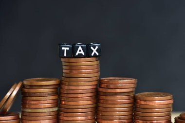 Tahta arka planda para yığınları ve plastik boncuklardan yapılmış sözcük vergisi. Para ekonomisi, vergi fikri, kopyalama alanı