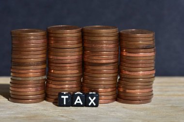 Tahta arka planda dört sütuna para yığılmış ve plastik boncuklardan yapılmış sözcük vergisi. Para ekonomisi, vergi fikri, kopyalama alanı