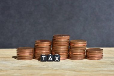 Tahta arka planda beş sütuna para yığılmış ve plastik boncuklardan yapılmış sözcük vergisi. Para ekonomisi, vergi fikri, kopyalama alanı