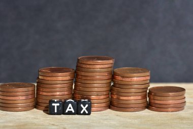 Tahta arka planda beş sütuna para yığılmış ve plastik boncuklardan yapılmış sözcük vergisi. Para ekonomisi, vergi fikri, kopyalama alanı