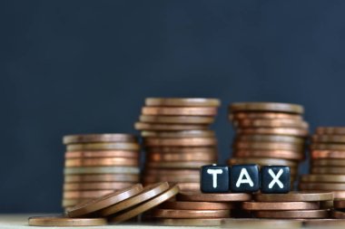 Tahta arka planda para yığınları ve plastik boncuklardan yapılmış sözcük vergisi. Para ekonomisi, vergi fikri, kopyalama alanı