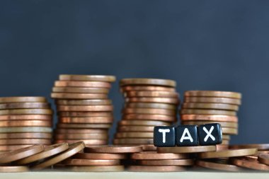 Tahta arka planda para yığınları ve plastik boncuklardan yapılmış sözcük vergisi. Para ekonomisi, vergi fikri, kopyalama alanı