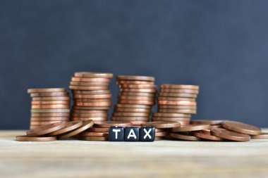 Tahta arka planda para yığınları ve plastik boncuklardan yapılmış sözcük vergisi. Para ekonomisi, vergi fikri, kopyalama alanı