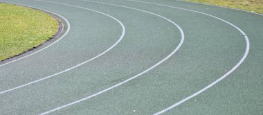 Beyaz çizgileri ve yeşil çimenleri olan yeşil koşu yolu eğrisi. Okul stadyumu spor pisti.