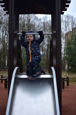 Küçük çocuk baharda çocuk parkında kaymaya hazır. Çocuk baharda parkta eğleniyor..