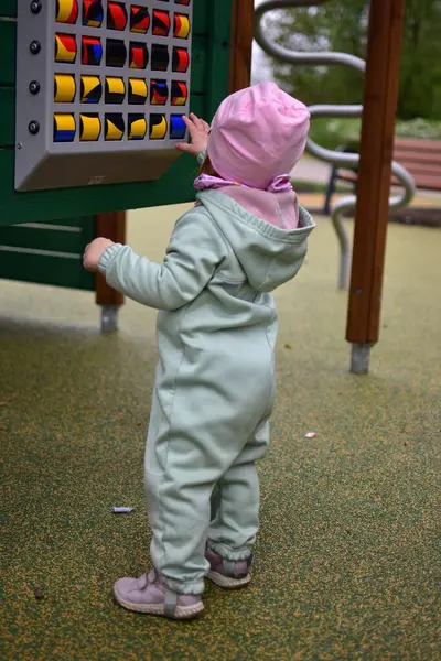 Yavru kız, soğuk baharda parktaki çocuk parkında bulmaca kaydırma oyunuyla oynuyor. Halka açık oyun parkında oyun ekipmanları sürülüyor. Yüz tanımlanamayan kişi yok..