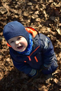 Ufaklık ağzını açıp ağaç dallarıyla oynayıp güneşli sonbahar bahar günlerinde ağaçtan düşen yapraklarda parkta oturuyor. Çocuk hayal gücünü kullanarak dışarıda eğleniyor..