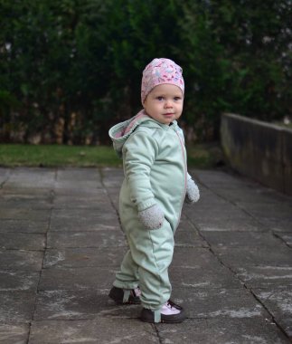 Nane kokulu, yumuşak kabuklu bebek baharda arka bahçede oynuyor. Küçük kız fayansların üzerinde yürüyor..