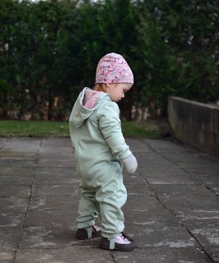 Nane kokulu, yumuşak kabuklu bebek baharda arka bahçede oynuyor. Küçük kız fayansların üzerinde yürüyor..