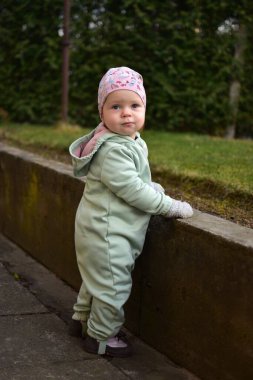 Nane kokulu, yumuşak kabuklu bebek baharda arka bahçede oynuyor. Küçük kız fayansların üzerinde yürüyor..