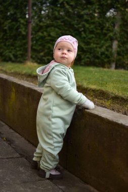 Nane kokulu, yumuşak kabuklu bebek baharda arka bahçede oynuyor. Küçük kız fayansların üzerinde yürüyor..