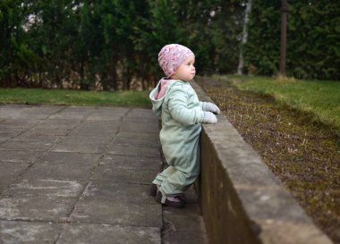 Nane kokulu, yumuşak kabuklu bebek baharda arka bahçede oynuyor. Küçük kız fayansların üzerinde yürüyor..