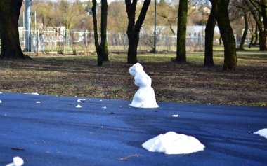 Baharda şehir parkındaki çocuk parkında neredeyse eriyen kardan adam. Üzgün bakışlı kardan adam kışın bitmesini bekliyor..
