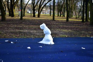Baharda şehir parkındaki çocuk parkında neredeyse eriyen kardan adam. Üzgün bakışlı kardan adam kışın bitmesini bekliyor..